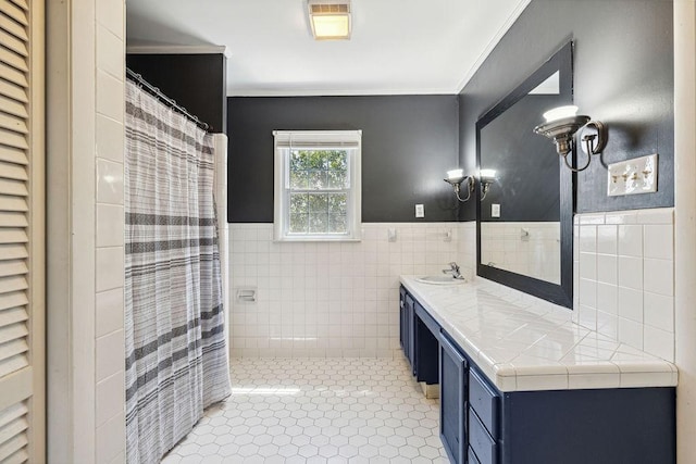 full bathroom featuring a shower with shower curtain, vanity, tile patterned floors, crown molding, and tile walls