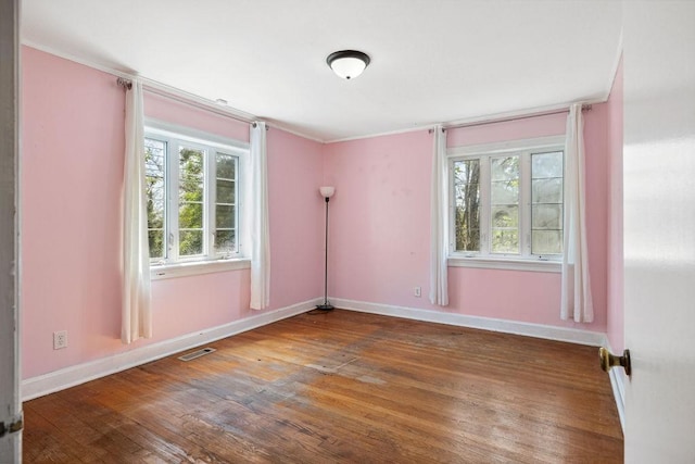 empty room with visible vents, baseboards, hardwood / wood-style floors, and crown molding