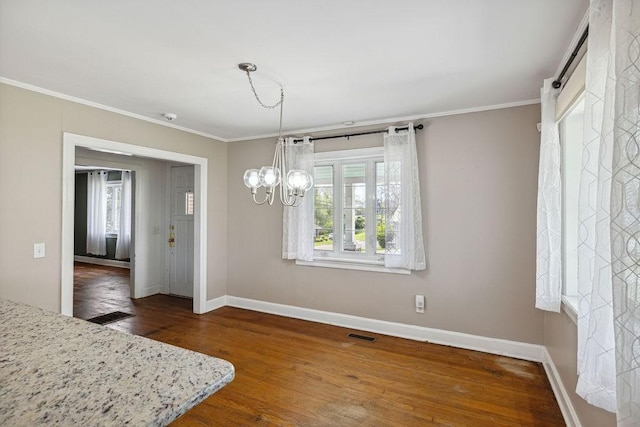 unfurnished dining area with visible vents, baseboards, a notable chandelier, crown molding, and wood finished floors