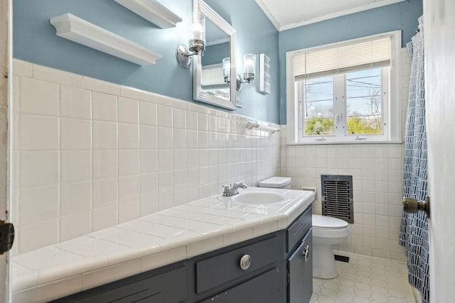 full bath featuring toilet, tile walls, crown molding, wainscoting, and vanity