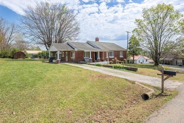 ranch-style home with an outbuilding, a front lawn, brick siding, a chimney, and driveway
