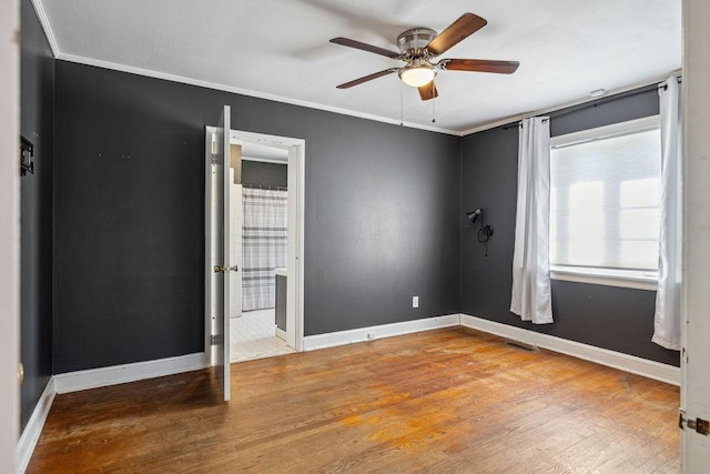 unfurnished bedroom featuring ceiling fan, ornamental molding, visible vents, wood finished floors, and baseboards