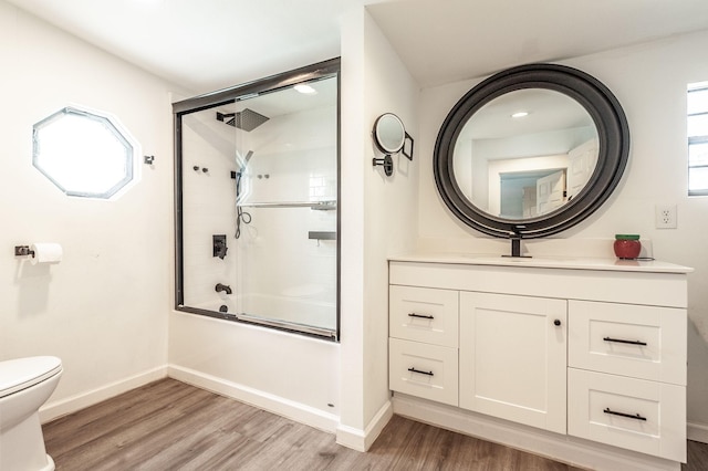 full bathroom with toilet, combined bath / shower with glass door, wood finished floors, and baseboards