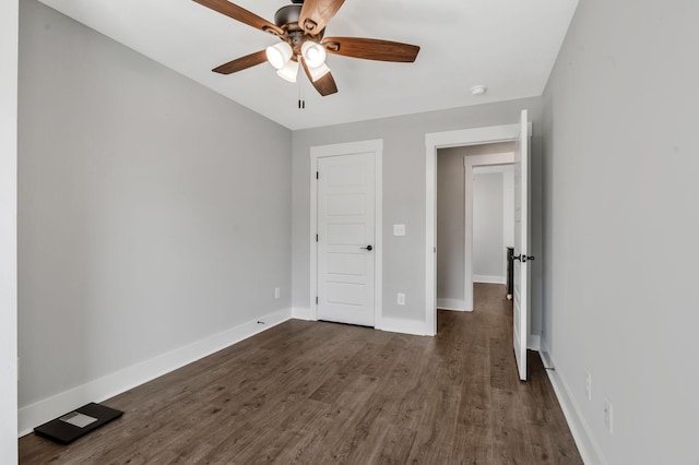unfurnished bedroom featuring dark wood-type flooring, ceiling fan, and baseboards