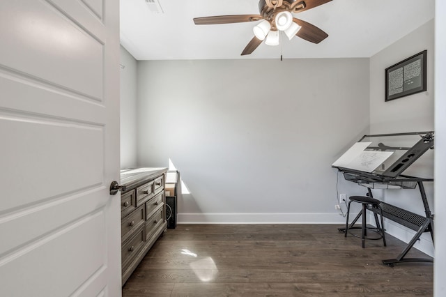 unfurnished office featuring dark wood-style flooring, baseboards, and a ceiling fan