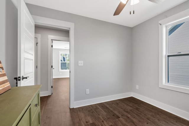 spare room featuring ceiling fan, baseboards, and dark wood finished floors