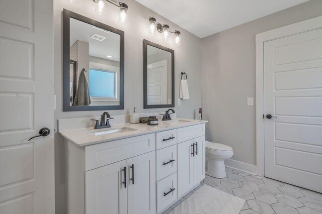 full bath with toilet, double vanity, a sink, and visible vents
