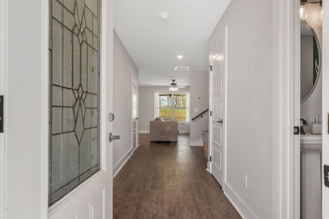 hallway with dark wood-type flooring, visible vents, baseboards, and recessed lighting