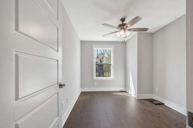 spare room featuring dark wood-style flooring, baseboards, and a ceiling fan