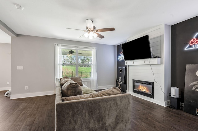 living room featuring a fireplace, dark wood-style flooring, baseboards, and a ceiling fan