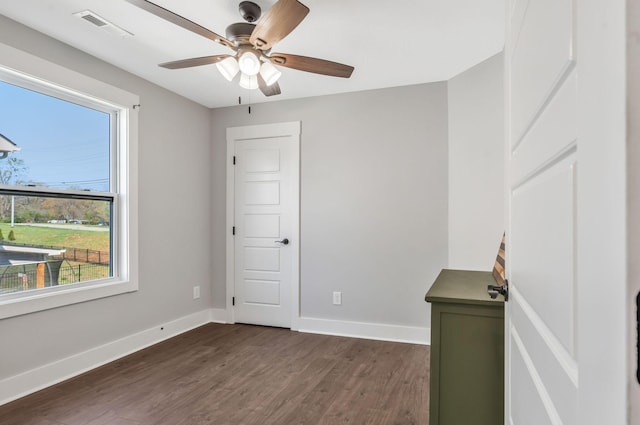 spare room featuring dark wood-type flooring, visible vents, baseboards, and ceiling fan