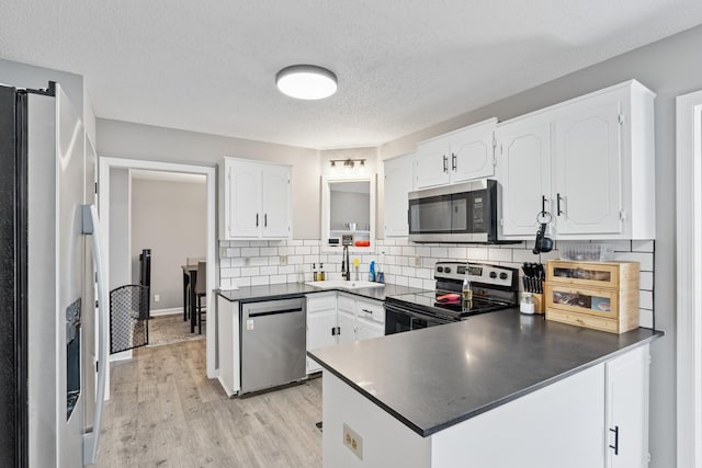 238 Kathleen Ct, Clarksville, TN 37043 - kitchen with a peninsula, white cabinetry, appliances with stainless steel finishes, a sink, and dark countertops