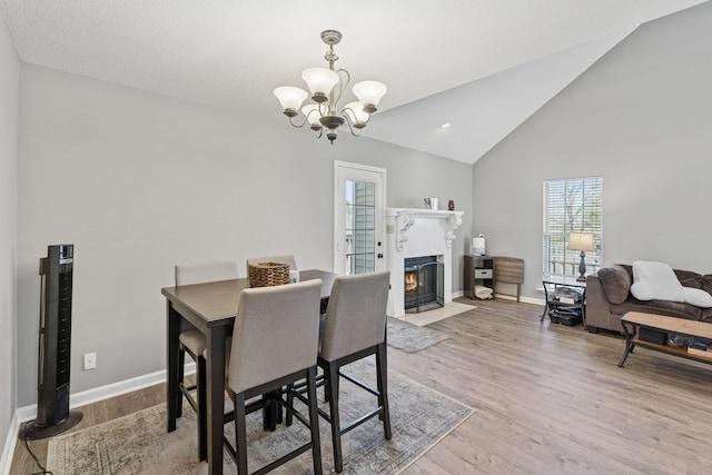 238 Kathleen Ct, Clarksville, TN 37043 - dining space featuring a notable chandelier, baseboards, a fireplace with flush hearth, high vaulted ceiling, and wood finished floors