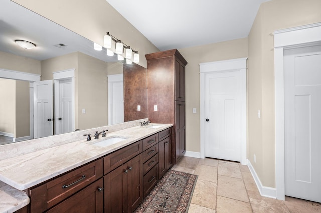 15 Westlawn Ct, Nashville, TN 37209 - bathroom featuring baseboards, double vanity, a sink, and stone tile flooring