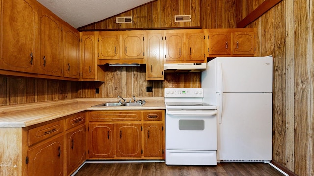 kitchen featuring white appliances, under cabinet range hood, a sink, lofted ceiling, and wooden walls