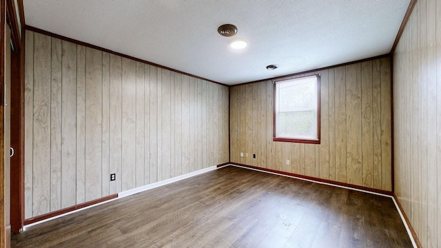 spare room with a textured ceiling, wood finished floors, and ornamental molding