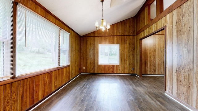 unfurnished room featuring wood-type flooring, wooden walls, a notable chandelier, and vaulted ceiling