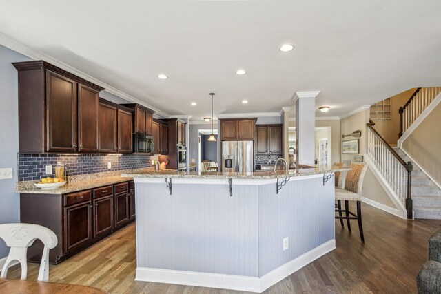 1702 Stoney Hill Ln, Spring Hill, TN 37174 - kitchen featuring a kitchen breakfast bar, light stone counters, wood finished floors, tasteful backsplash, and appliances with stainless steel finishes