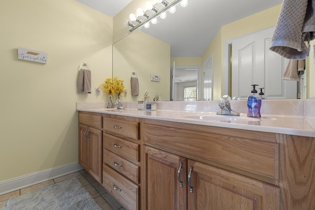 full bathroom with a sink, baseboards, double vanity, and tile patterned flooring