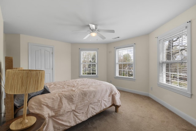 bedroom featuring visible vents, light colored carpet, baseboards, and a ceiling fan