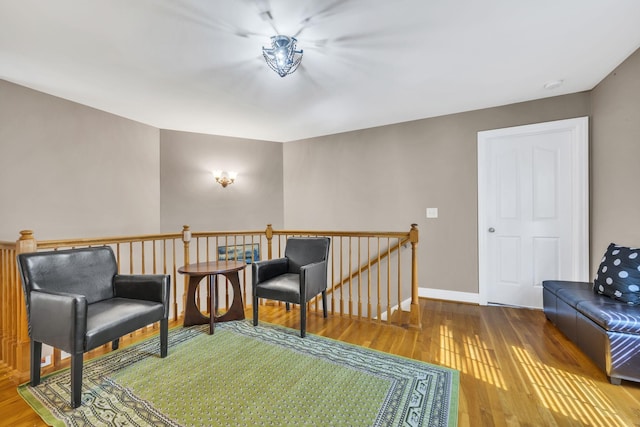 sitting room featuring baseboards, an upstairs landing, and wood finished floors