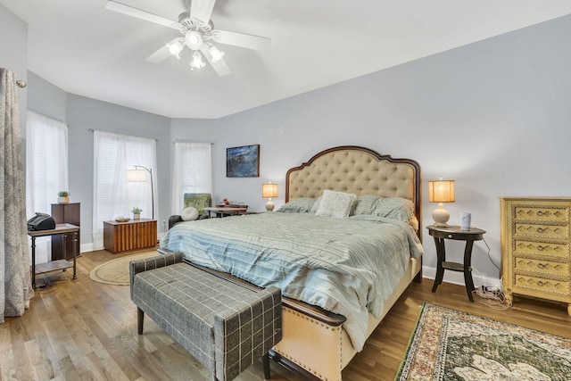 bedroom with wood finished floors, baseboards, and multiple windows