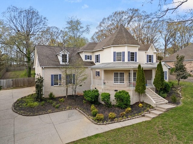 victorian house with a porch, roof with shingles, a front yard, fence, and stairs