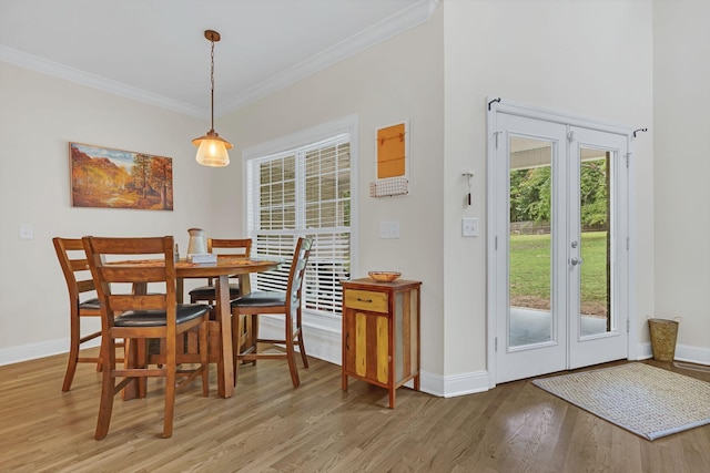 dining area featuring light wood finished floors, baseboards, and crown molding