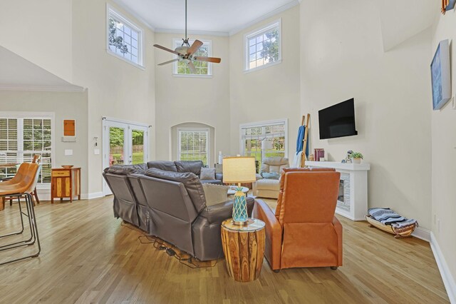 living area featuring french doors, baseboards, wood finished floors, ceiling fan, and crown molding