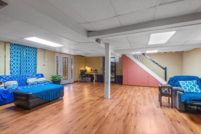 finished below grade area with stairway, light wood-style floors, a drop ceiling, and visible vents