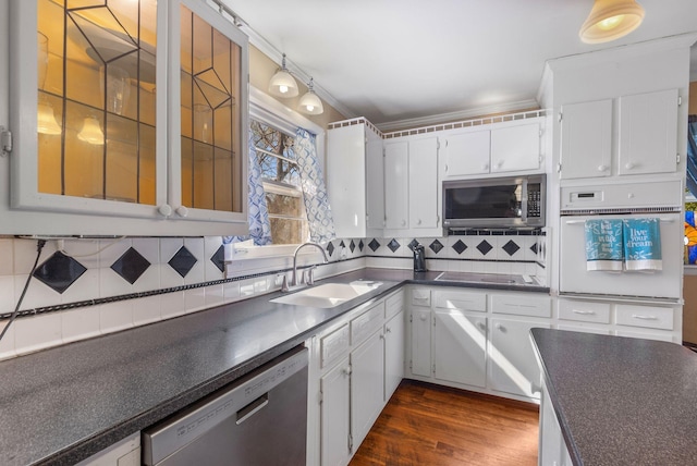 kitchen featuring tasteful backsplash, white cabinetry, dark countertops, a sink, and stainless steel appliances