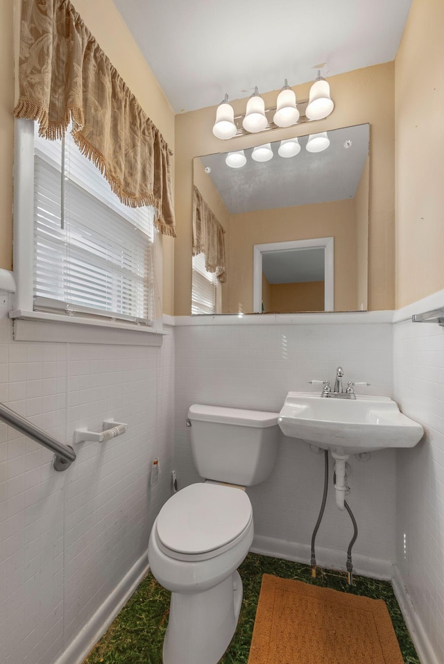 half bath featuring toilet, tile walls, and a wainscoted wall