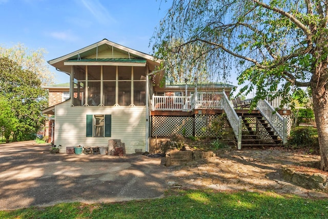 back of property featuring stairway, a wooden deck, and a sunroom