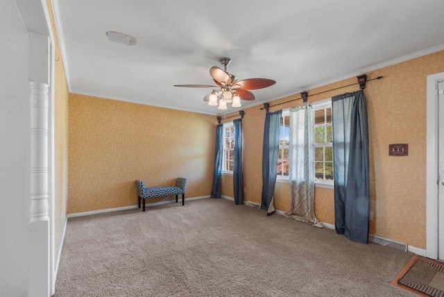 carpeted spare room with crown molding, wallpapered walls, baseboards, and a ceiling fan