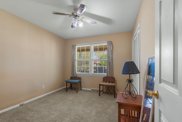 living area with light colored carpet, ceiling fan, and baseboards