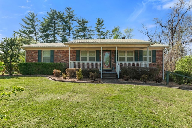 ranch-style home with a front yard, metal roof, brick siding, and covered porch