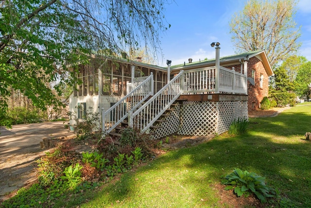 rear view of house with brick siding, a yard, stairway, and a wooden deck