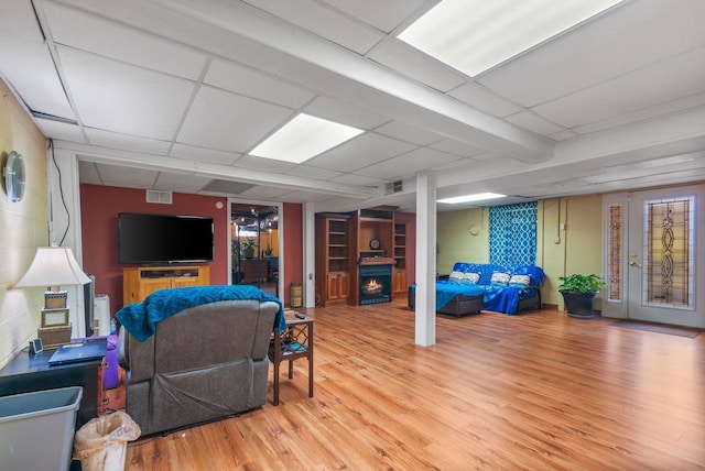 living area with visible vents, light wood finished floors, and a lit fireplace