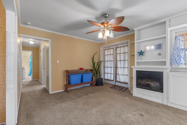 unfurnished living room featuring a ceiling fan, a glass covered fireplace, ornamental molding, and carpet