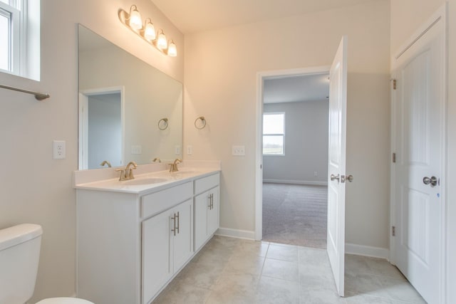 bathroom with tile patterned flooring, double vanity, a sink, and toilet