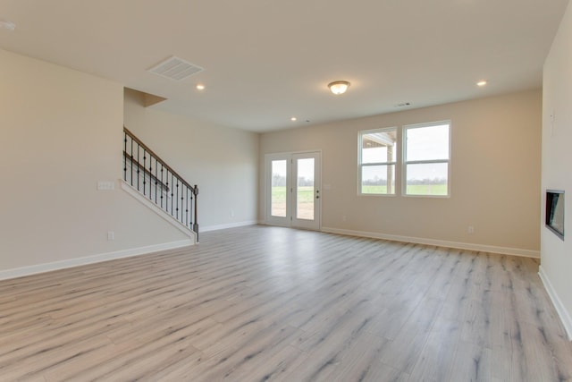 unfurnished living room with visible vents, baseboards, light wood-type flooring, recessed lighting, and stairs