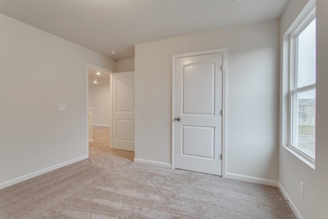 unfurnished bedroom with baseboards and light colored carpet