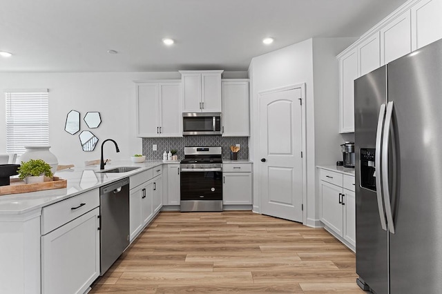 8547 Turnbull Dr, Pleasant View, TN 37146 - kitchen with appliances with stainless steel finishes, a peninsula, light wood finished floors, white cabinets, and tasteful backsplash