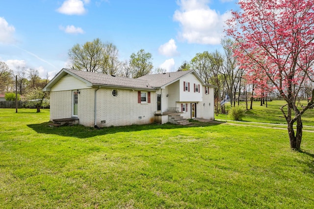back of property featuring brick siding, a yard, crawl space, and roof with shingles