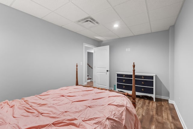 bedroom with visible vents, baseboards, a paneled ceiling, and wood finished floors