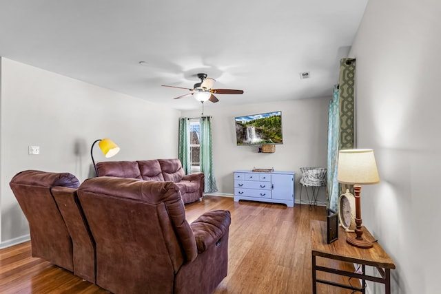 living room featuring wood finished floors, baseboards, a ceiling fan, and visible vents