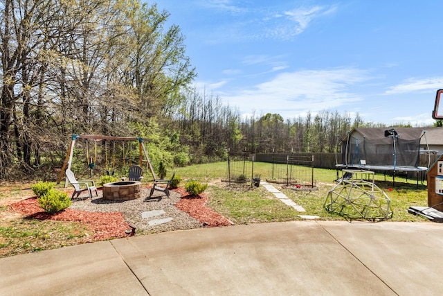 view of yard featuring fence, a trampoline, a fire pit, and a patio