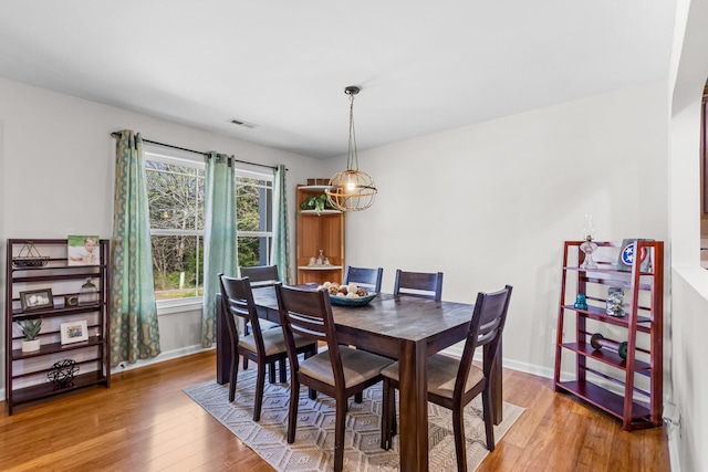 dining space with wood finished floors, baseboards, and visible vents