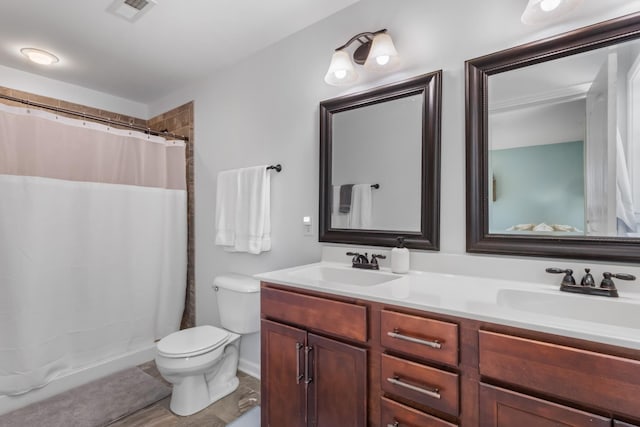 bathroom featuring double vanity, visible vents, a sink, and toilet