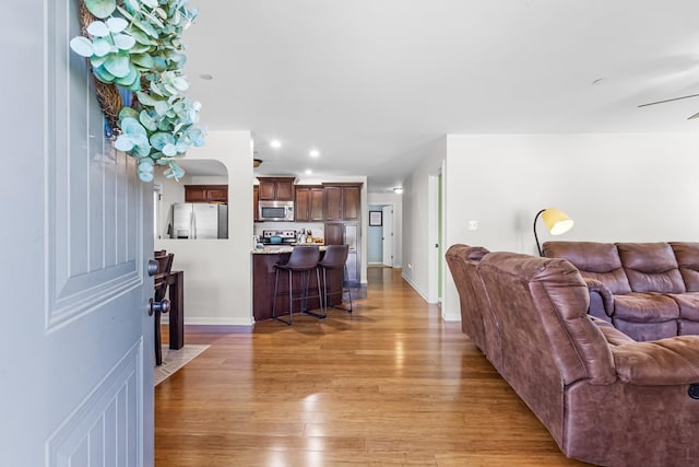 living room with recessed lighting, light wood finished floors, baseboards, and ceiling fan